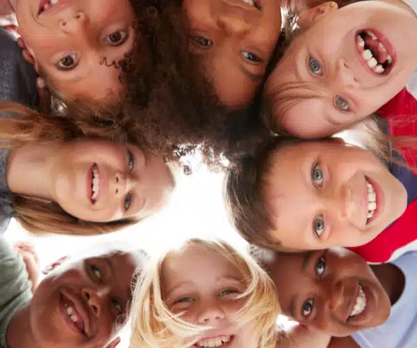 Groupe d’enfants souriants formant un cercle vu du dessous, participant à une animation ludique et collective