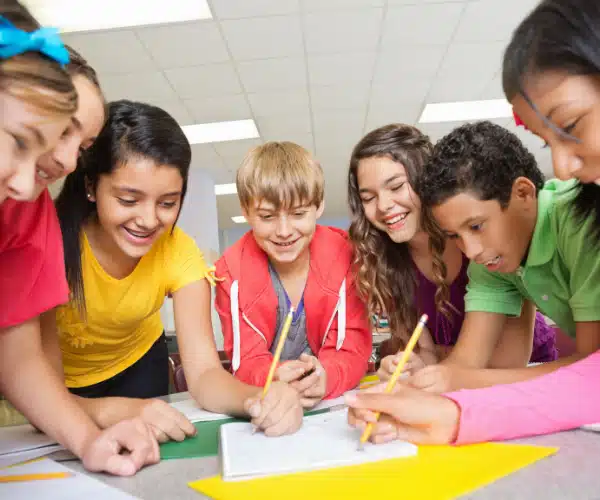Élèves de primaire réunis autour d’une table, résolvant des énigmes en groupe dans le cadre d’un escape game pédagogique