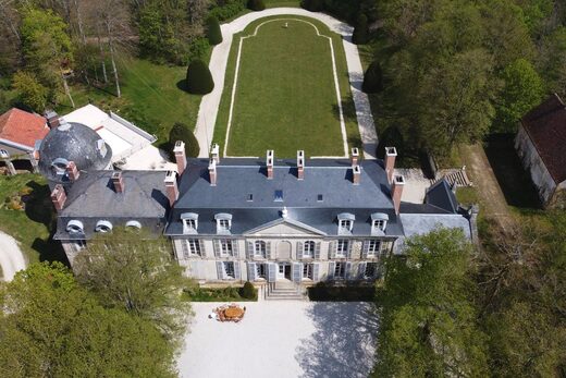 Vue aérienne d'un domaine historique entouré de verdure.
